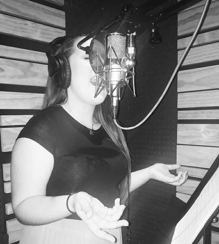 Singing in recording booth in front of microphone